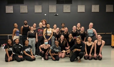 A group of dancers poses together in a dance studio.